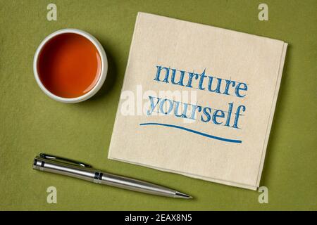nutritevi voi stessi - calligrafia ispiratrice su un tovagliolo con una tazza di tè, concetto di cura di sé Foto Stock
