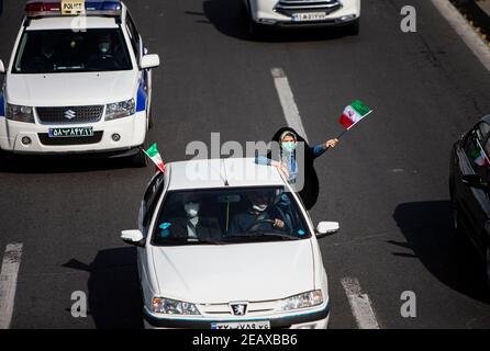 Teheran, Iran. 10 Feb 2021. Una donna detiene una bandiera dell'Iran durante un raduno per celebrare il 42° anniversario della vittoria della rivoluzione islamica a Teheran, Iran, il 10 febbraio 2021. Mercoledì gli iraniani hanno partecipato a raduni nazionali per celebrare il 42° anniversario della vittoria della rivoluzione islamica. Credit: Ahmad Halabisaz/Xinhua/Alamy Live News Foto Stock