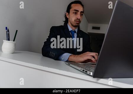 uomo d'affari che lavora a casa in tuta blu monocromatica, giorno di lavoro, sensazione di vertigine Foto Stock