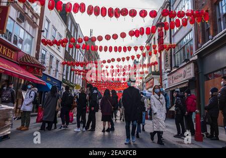 La gente che indossa le maschere facciali come misura preventiva contro la diffusione della coda di covid-19 nel negozio cinese di fronte a China Town, London.Chinese New Year è il più grande festival in Asia. Ogni anno, centinaia di migliaia di persone solitamente discendono sul West End di Londra per godere di una sfilata colorata, spettacoli di palcoscenico libero e piatti tradizionali cinesi, e per augurarsi a vicenda 'Xin Nian Kuai le' (Felice anno nuovo in Mandarino) o 'San Nin Faai Lok' (in Cantonese). A causa delle restrizioni nazionali di blocco, le persone possono godersi l'intrattenimento di Capodanno cinese di Londra da casa con una celebrazione online del passato C. Foto Stock