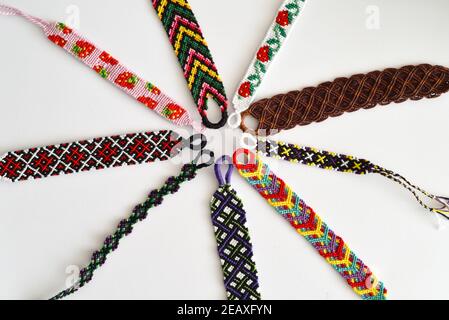 Braccialetti fai-da-te intrecciati realizzati a mano con filo lucido ricamato con nodi isolati su sfondo bianco. Foto Stock