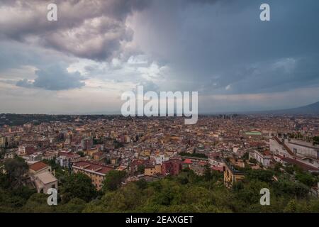 Vista panoramica sugli edifici e sul verde della città di Napoli, Italia meridionale, durante un tramonto nuvoloso. Foto Stock