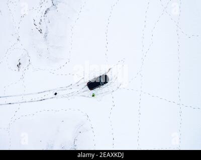 Vista aerea di un'auto parcheggiata su un campo innevato coperto di impronte in inverno Foto Stock