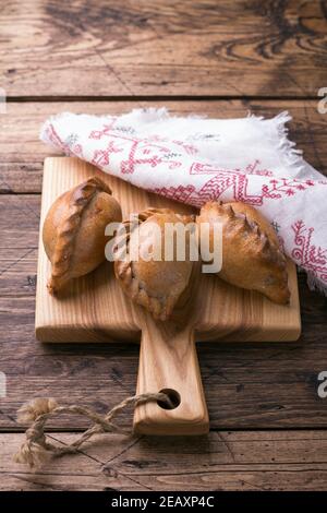 Torte di segala tradizionali russe con uova, kokurki, su un tavolo di legno, stile rustico, verticale. Deliziosi piatti e spuntini fatti in casa Foto Stock