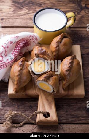 Torte di segala tradizionali russe con uova, kokurki, su un tavolo di legno, stile rustico. Deliziosi piatti e spuntini fatti in casa Foto Stock