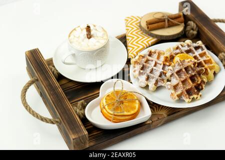 Prima colazione, caffè con marshmallows e un bastone di cannella E i waffle belgi giacciono su un vassoio di legno Foto Stock