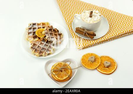 Prima colazione, caffè con marshmallows e un bastone di cannella E cialde belghe giacciono su un tavolo Foto Stock