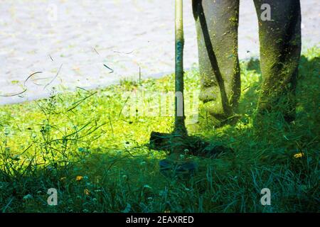 taglio erba verde lussureggiante nel parco. splendido sfondo natura. cura del prato lavoro in corso concetto. spazzola utensile utilizzato per mantenere giardini e. Foto Stock