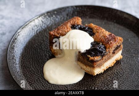 Torta di prugna secca e noce con crema alla vaniglia Foto Stock