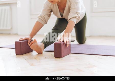 Bella donna di mezza età in abbigliamento sportivo pactice yoga con attrezzature in studio luminoso Foto Stock