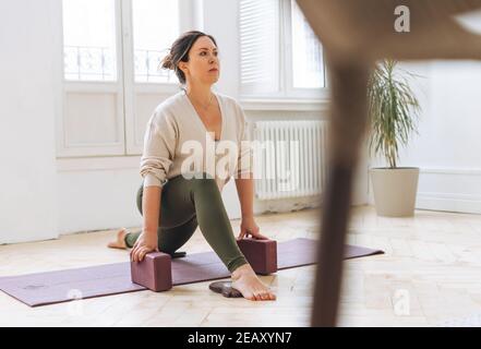 Bella donna bruna di mezza età in sportswear pactice yoga con attrezzature in studio luce Foto Stock