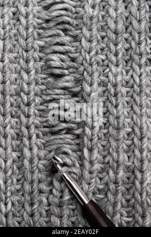 Tessitura a maglia grigio chiaro con difetto di fabbricazione isolato su bianco Foto Stock