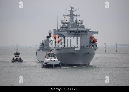 Tugs scortano la Royal Fleet Auxiliary nave ARGUS come esso Arriva alla base navale la mattina presto Foto Stock