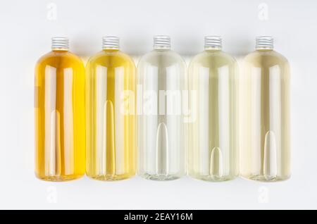 Raccolta bottiglie trasparenti con diversi colori chiari prodotto cosmetico liquido, profumo o bevanda, bolla e tappo argento su sfondo bianco, mockup Foto Stock