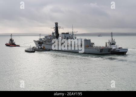 Il Royal Navy Type 23 fregate HMS IRON DUKE, spogliato di gran parte delle sue attrezzature, lascia il porto sotto il rimorchio Foto Stock