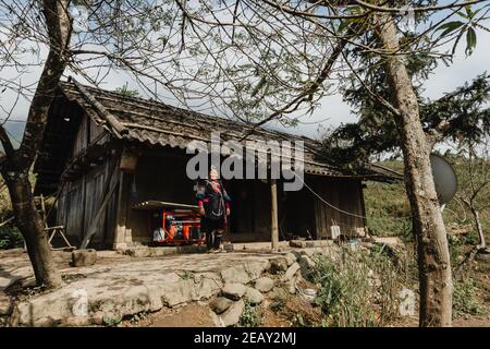 Una minoranza etnica Indigo Hmong donna è in piedi di fronte alla sua casa in un villaggio del nord del Vietnam. Foto Stock