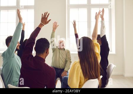 Gruppo di persone felici che siedono in cerchio in riunione di comunità e votando per un buon suggerimento Foto Stock