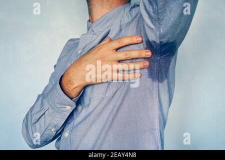 Uomo con iperidrosi sudorazione molto male sotto ascella in camicia blu. Punto bagnato sulla mia camicia da sudore. Foto Stock