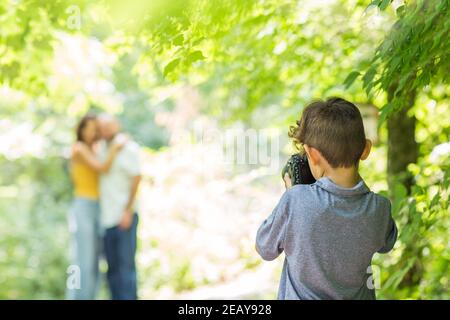 Ragazzino che fotografa i suoi genitori nei boschi. Foto Stock