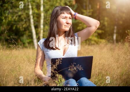 giovane donna adulta guarda un laptop in un panico e tiene la testa. problema di rete. shock contenuto Foto Stock