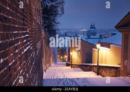Paesaggio urbano di Praga in inverno. Scalinata storica illuminata contro la città bassa e la città vecchia al mattino presto. Foto Stock
