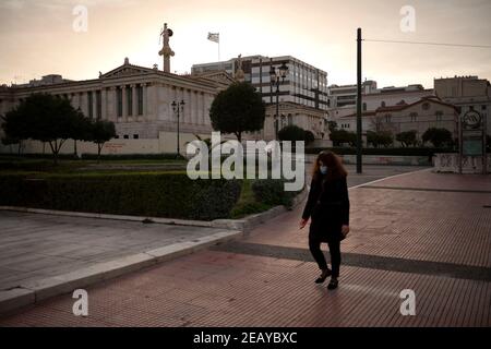 Athen, Grecia. 11 Feb 2021. Una donna cammina di fronte all'università. Da giovedì mattina, la zona di Atene è stata nuovamente sottoposta a un duro blocco per contenere la pandemia di Corona, il cui rispetto è imposto dalla polizia con numerosi blocchi stradali. Credit: Angelos Tzortzinis/dpa/Alamy Live News Foto Stock