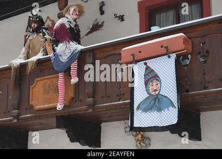 Farchant, Germania. 11 Feb 2021. Le figure tradizionali del carnevale, solitamente indossate dalla gente del posto nella tradizionale Maschkera-Gehen, sono decorate su un balcone. Quest'anno, streghe, gnomi, campanili e altri personaggi del carnevale sono a casa - e così nella città alta bavarese di Farchant, figure con maschere storiche vi accolgono dalle finestre o dai balconi. Credit: Angelika Warmuth/dpa/Alamy Live News Foto Stock