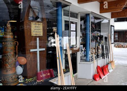 Farchant, Germania. 11 Feb 2021. Una bara di legno con costumi solitamente indossati dalla gente del posto alla tradizionale passeggiata Maschkera si trova nella vetrina di un negozio di ferramenta con l'iscrizione 'Ecco il nostro amato Farchanter Fasenach'. Quest'anno, streghe, gnomi, campanili e altri personaggi del carnevale sono a casa - e così nella città alta bavarese di Farchant, figure con maschere storiche vi accolgono dalle finestre o dai balconi. Credit: Angelika Warmuth/dpa/Alamy Live News Foto Stock