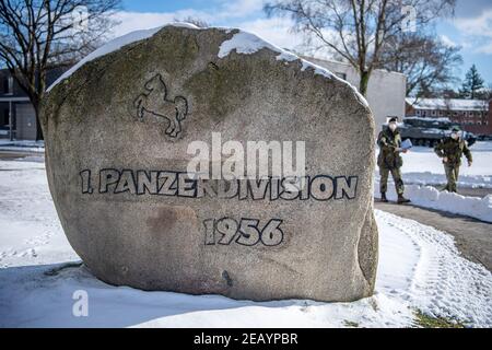 Oldenburg, Germania. 11 Feb 2021. I soldati della Bundeswehr camminano oltre una pietra con l'iscrizione '1. PanzerDivision 1956'. La prima divisione armata di Oldenburg sta organizzando assistenza nella pandemia di Corona in cinque stati tedeschi come comando regionale occidentale: Nord Reno-Westfalia, Assia, bassa Sassonia, Brema e Sassonia-Anhalt. Credit: Sina Schuldt/dpa/Alamy Live News Foto Stock