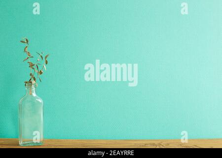 Eucalipto in bottiglia di vetro su tavolo di legno. Sfondo verde Foto Stock