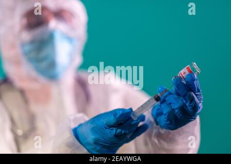 Mano del medico in guanti blu in nitrile che tengono vaccinato il coronavirus per malattie vaccinazione di scoppio Foto Stock