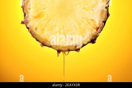 il succo di ananas appena spremuto scorre dalla fetta di frutta matura primo piano - su sfondo giallo Foto Stock