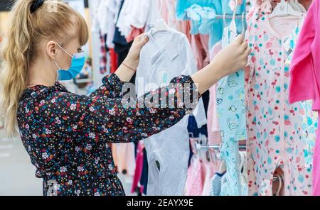 Donna sceglie i vestiti del bambino nel deposito. Messa a fuoco selettiva. Negozio. Foto Stock