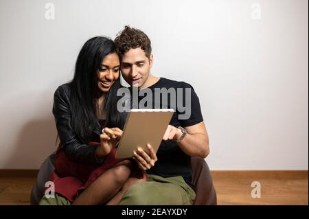 Coppia sorridente seduta sulla borsa dei fagioli mentre si guarda il tablet. Foto Stock