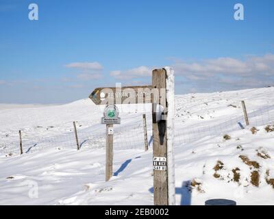 Pennine Way segno su palo di legno innevato brughiere e. cielo blu Foto Stock