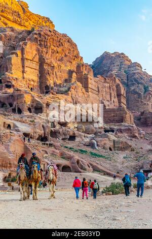 PETRA, GIORDANIA, 2 GENNAIO 2019: beduino che cavalcano un asino di fronte alla tomba dell'urna a petra, Giordania Foto Stock