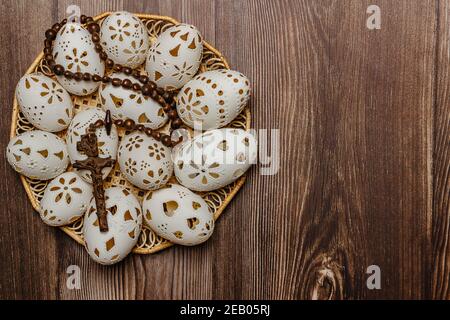 Happy Easter.White mano fatto uova di Pasqua con crocifisso in legno basket.Spring decorazione sfondo. Tradizione festosa per il simbolo cristiano.religioso Foto Stock