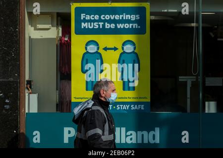 Watford, Regno Unito. 11 febbraio 2021. Un cartello che richiede l'uso di un facemask nella finestra di un negozio nel centro di Watford, mentre la pandemia del coronavirus continua. Il governo britannico sta tentando di raggiungere il suo obiettivo di 15 milioni di vaccini somministrati entro il 15 febbraio, con 13,5 milioni di vaccini somministrati finora. Credit: Stephen Chung / Alamy Live News Foto Stock