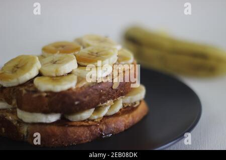 Pane tostato al miele di banana al burro di arachidi, un'idea facile per la colazione. Scatto su sfondo bianco. Foto Stock