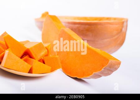 Succosa zucca arancione tagliata in pezzi diversi, su fondo bianco. Foto Stock