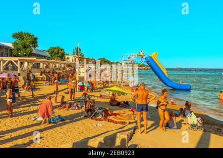 Un grande raduno di persone nella stagione estiva la spiaggia di sabbia nella città di villeggiatura Foto Stock