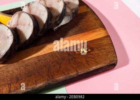 Sgombro fresco tritato giace su una tavola da cucina insieme con capsule di olio di fegato di merluzzo su uno sfondo luminoso Foto Stock