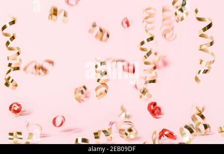 Coriandoli volanti dorati e rossi su sfondo rosa Foto Stock