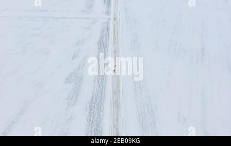 11 febbraio 2021, Schleswig-Holstein, Bornhöved: Una passeggiata pedonale su una strada completamente coperta di neve. Foto: Axel Heimken/dpa Foto Stock