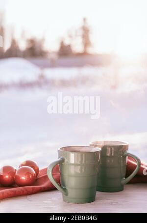 Tessera rustica vintage con tazze di tè in porcellana verde su tavolo di legno bianco decorato con palle di Natale rosse. Periodo invernale stagionale di vacanza. Foo Foto Stock