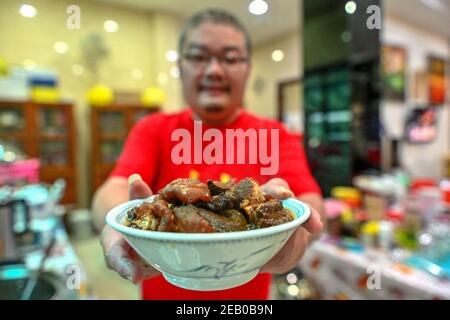 Kuala Lumpur, Malesia. 11 Feb 2021. Un uomo cinese mostra un piatto di Hakka alla vigilia del Festival di primavera a Kuala Lumpur, Malesia, 11 febbraio 2021. Credit: Chong Voon Chung/Xinhua/Alamy Live News Foto Stock