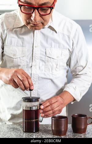 Uomo che prepara due tazze di caffè in una pressa francese Foto Stock