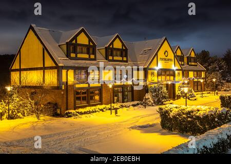 Gdansk, Oliwa, Polonia - 16 gennaio 2021 - Vista della città vecchia illuminata e innevata di Oliwa. Fishgarten Hotel. Foto Stock