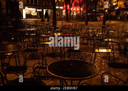 PARIGI, FRANCIA - 19 OTTOBRE 2019: Scena urbana notturna parigina dopo la pioggia. Le luci sfocate dei bar e dei negozi si riflettono sui tavoli e sui ciottoli vuoti dei caffè bagnati Foto Stock