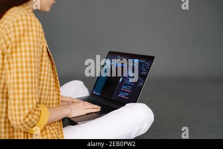 Giovane donna sviluppatore mobile scrive il codice del programma su un computer, lavoro del programmatore. Foto Stock